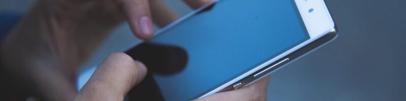 Close-up of a person using a smartphone with their thumb in the "Thumb Zone," demonstrating mobile-first web design optimization for local business search.