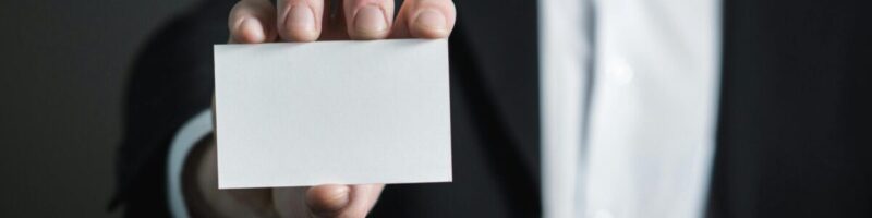 A professional holding a blank business card, symbolizing the need for consistent business identity and N.A.P. data in local SEO.
